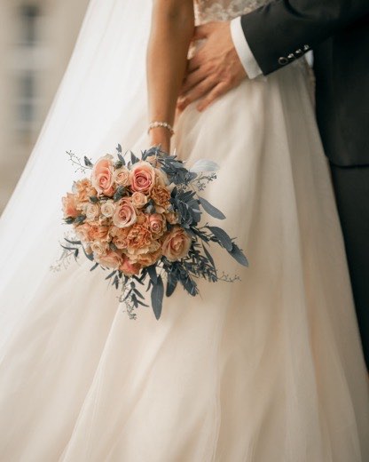 Brautstrauß mit Rosen vor dem Brautkleid