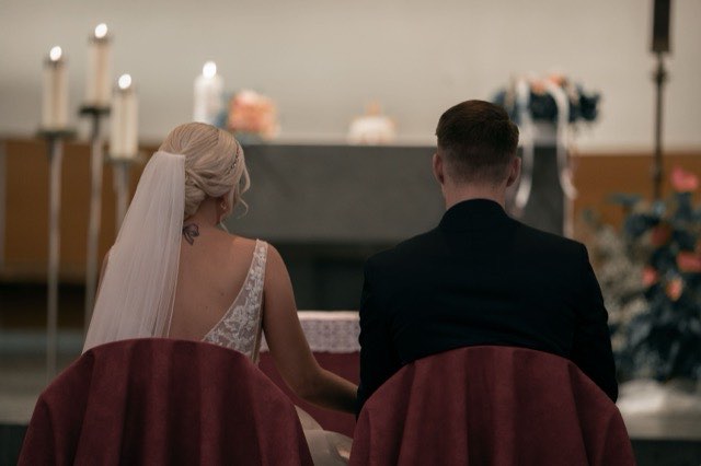 Brautpaar von hinten bei der Trauung in der Kirche